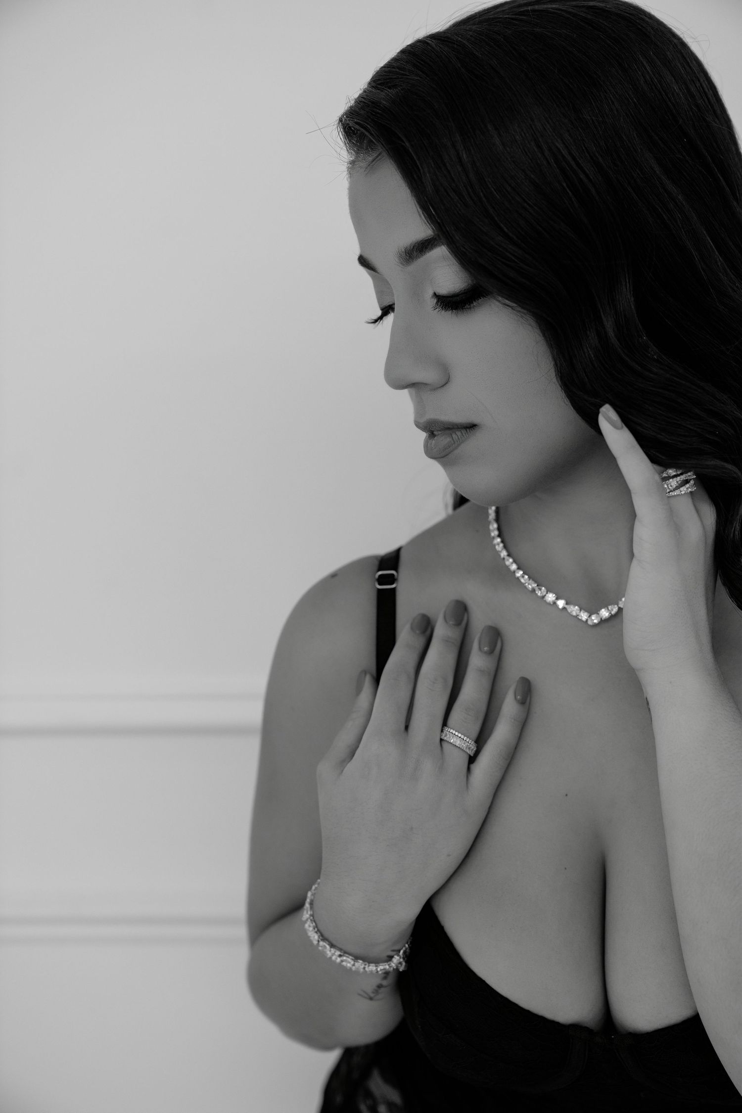Black and white portrait of a woman wearing a pearl necklace and bracelet, posing elegantly in a dark top.