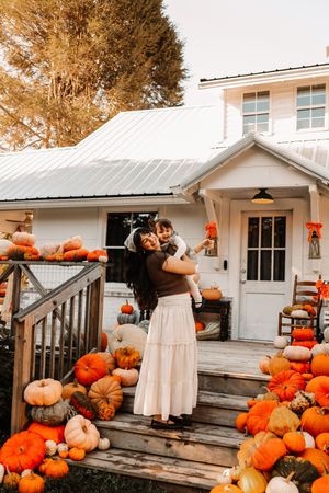 A woman in a white skirt holds a child at The Holmstead Studio in Karns, TN with Nina Thomas Photography.