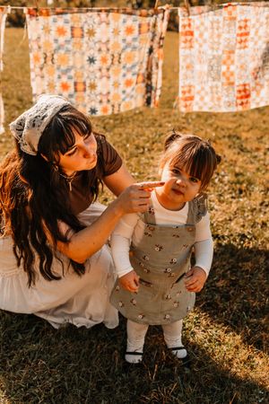 A mother and daughter with colorful quilts hanging on a clothesline at The Holmstead Studio in Karns, TN with Nina Thomas Photography.