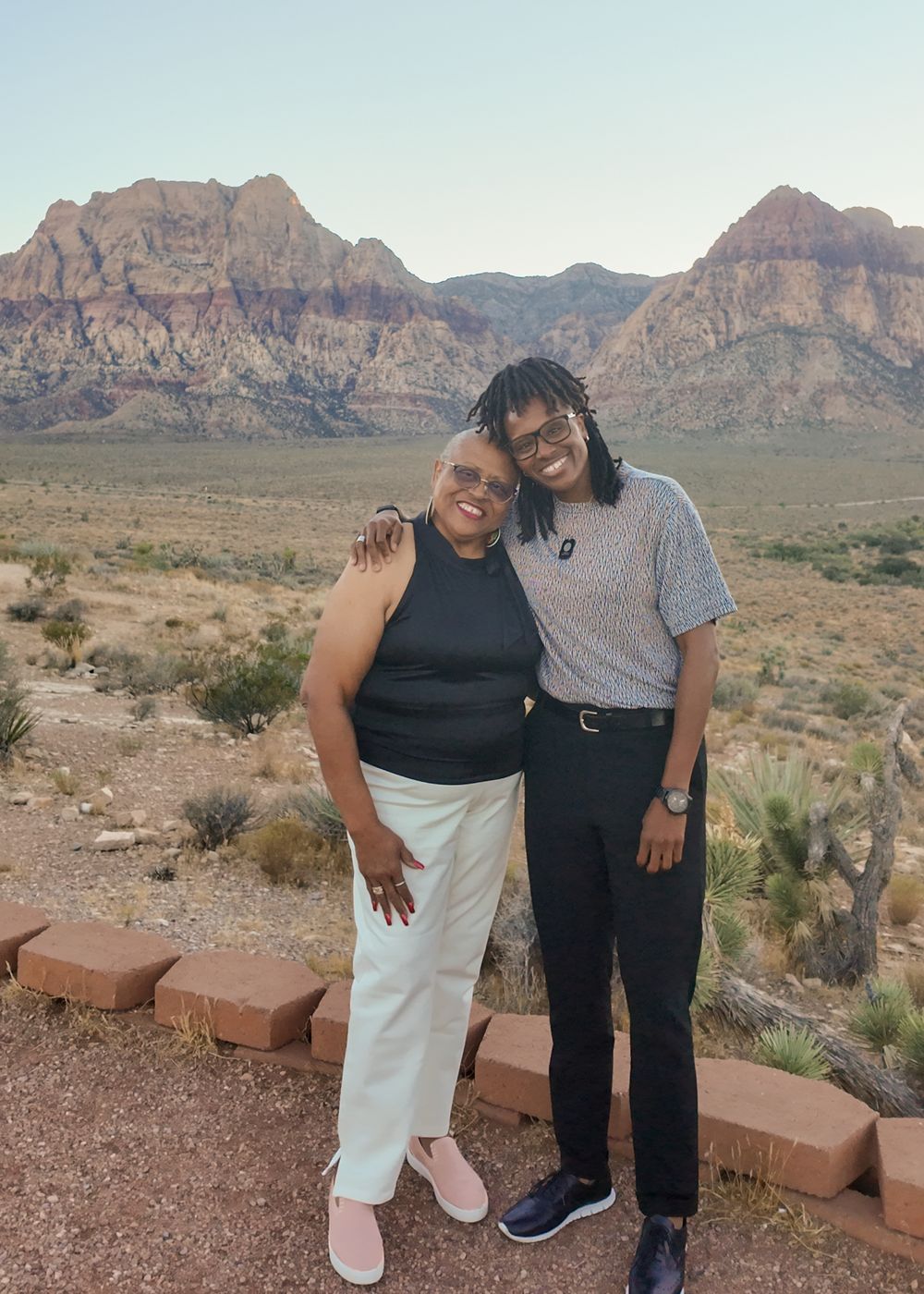 Two people smiling together at Red Rock Canyon, Nevada, with stunning desert mountains in the background.
