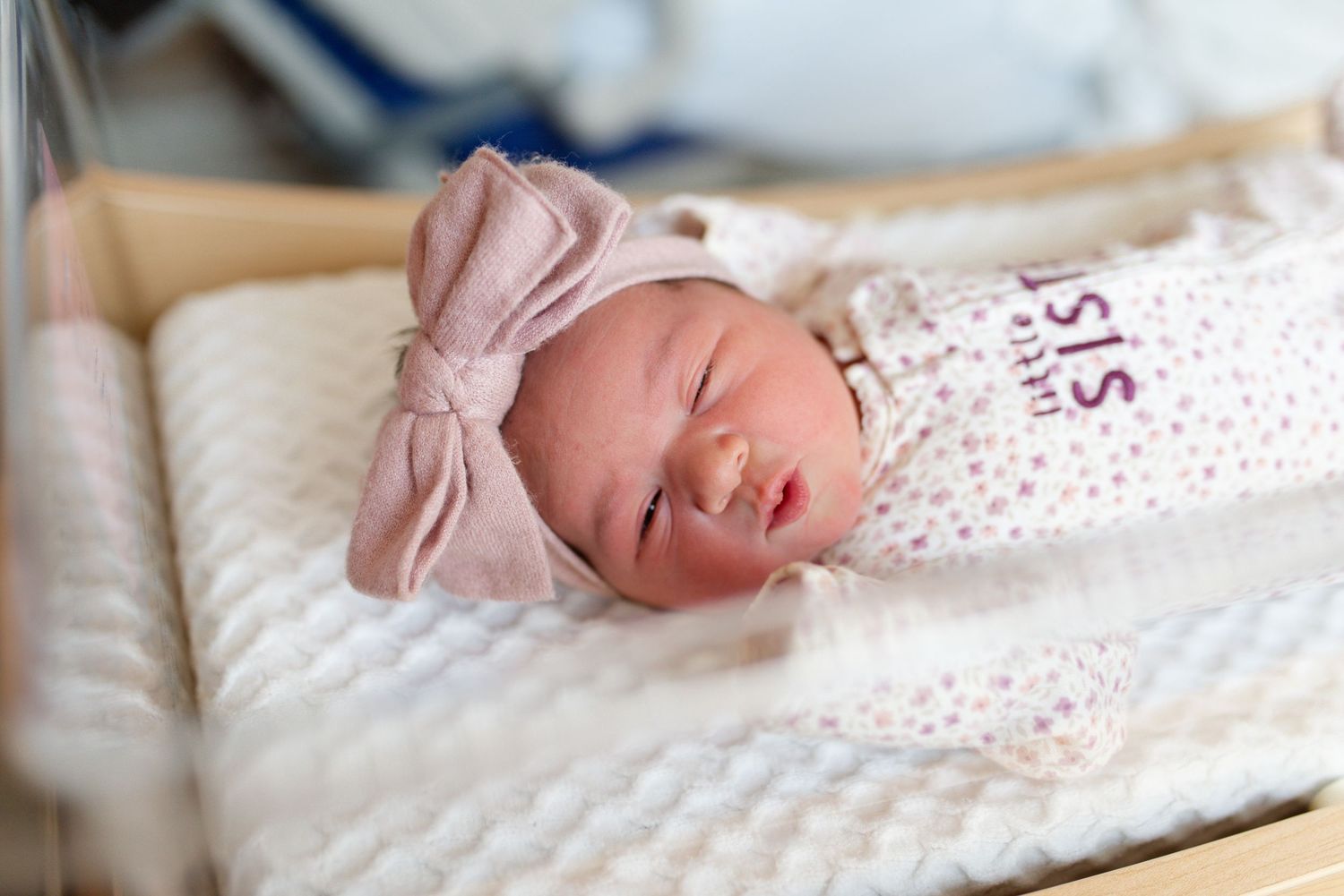 A couple sits in a nursery glider chair holding their newborn baby. St Louis Newborn Photographer