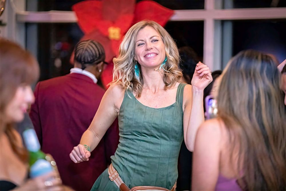 Woman in green dress dancing and smiling at a party.