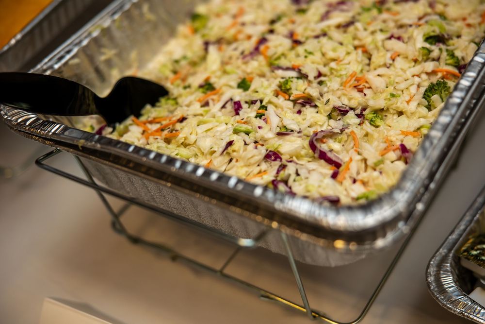 Catered fried rice with colorful vegetables in a large aluminum pan on a warming rack.