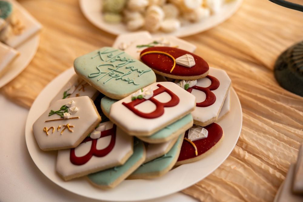 Decorated sugar cookies with red and mint green frosting featuring letter B designs on a white plate.