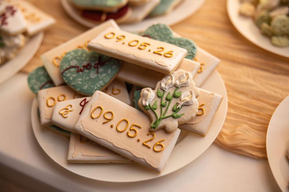 Decorated wedding cookies with date 09.05.26 and floral designs on a white plate.