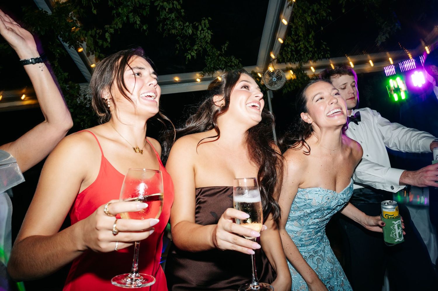 A group of wedding guests dancing and singing during reception celebration.