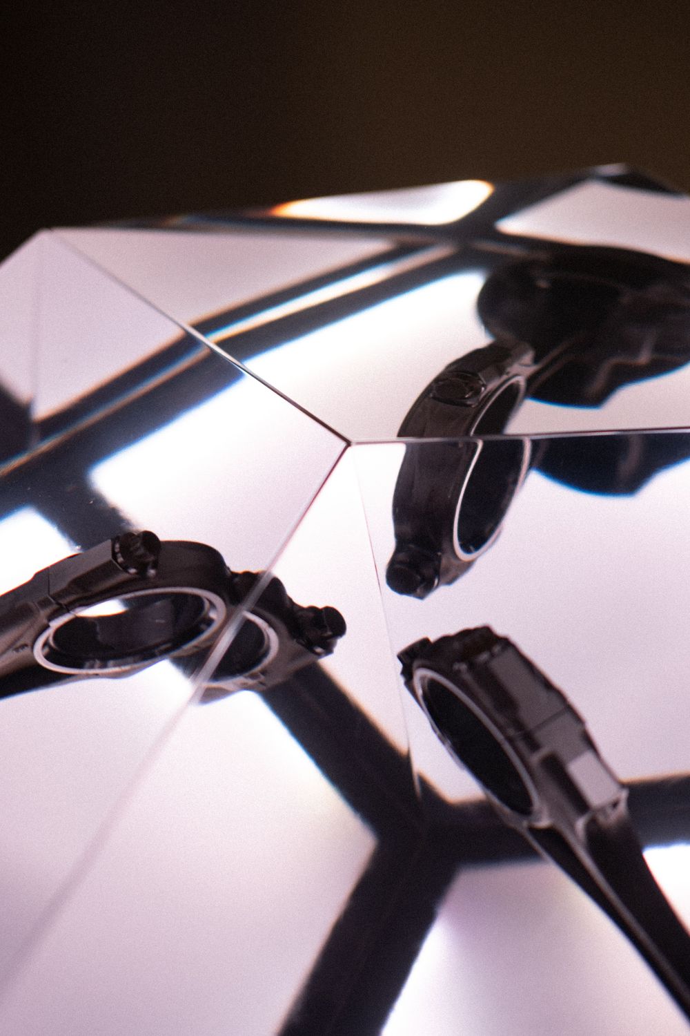 Close-up of a drone's black plastic motor mounts on illuminated white geometric panels with dramatic shadows.