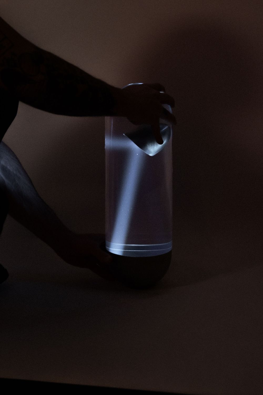 Hand holding a glowing illuminated lantern in a dark room, casting soft white light.