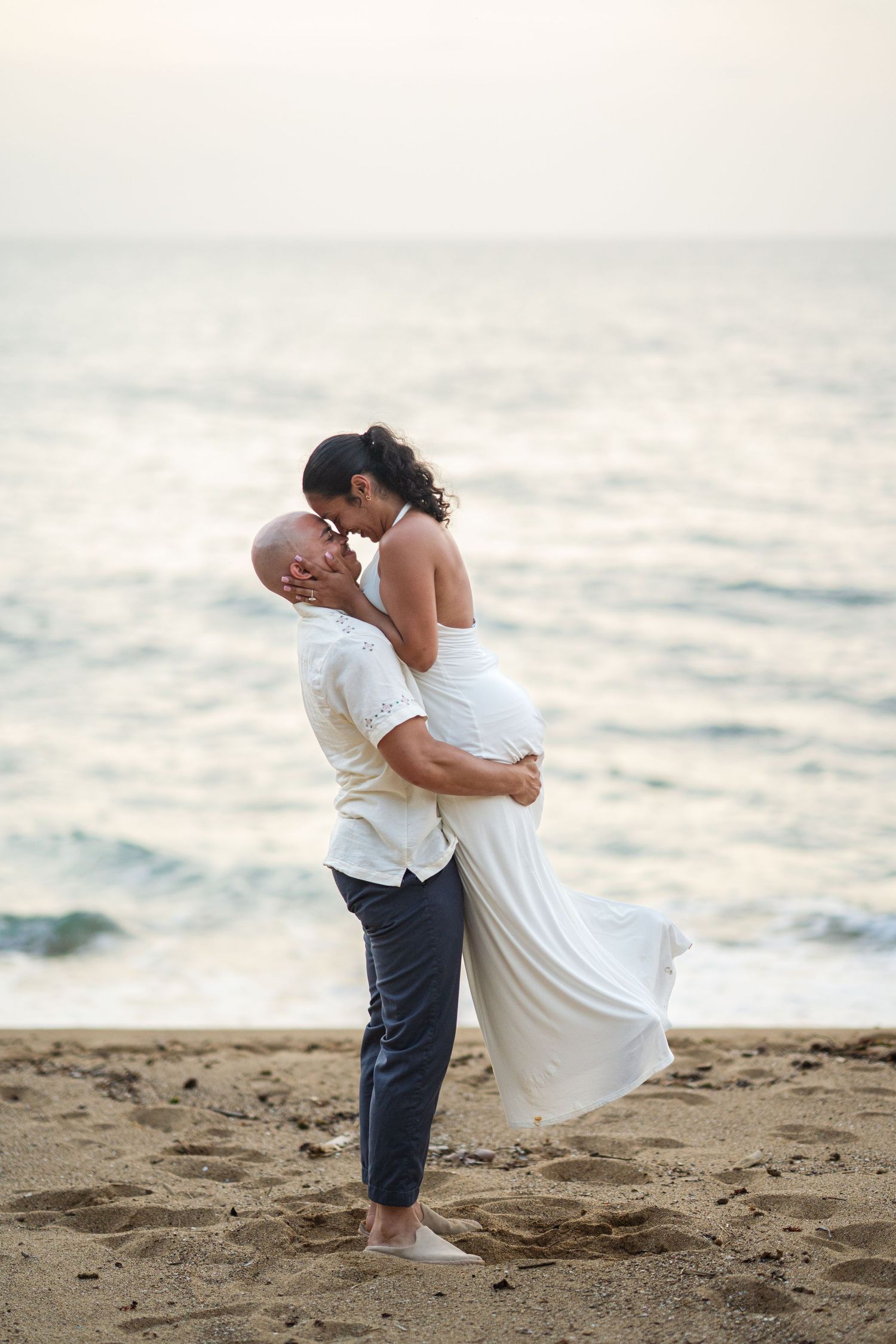 A couple sharing a romantic moment, the woman gently cupping the man's face as they lean in for a kiss outdoors.