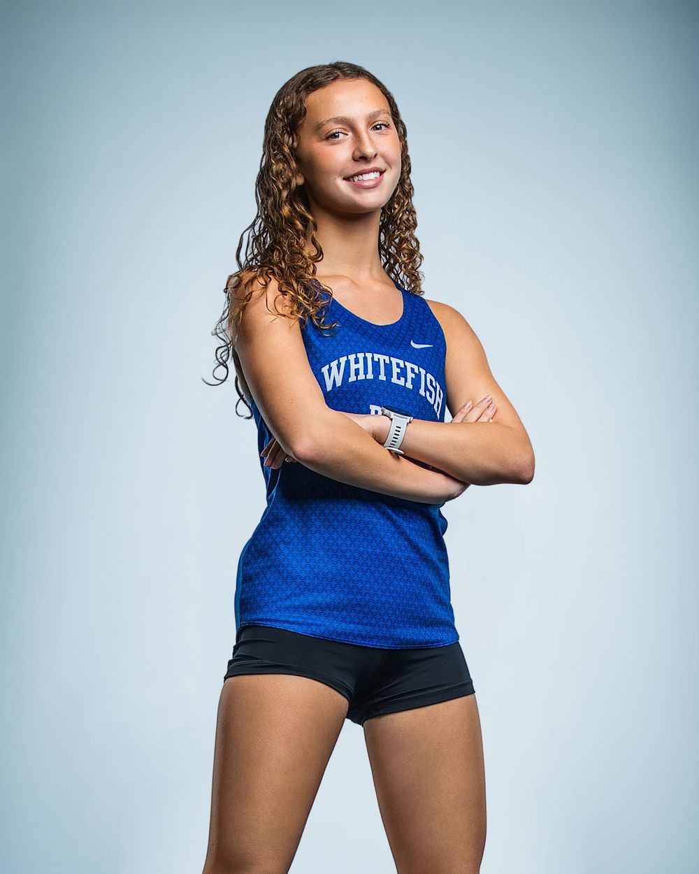Young female athlete in Whitefish blue Nike tank top poses with arms crossed for a sports portrait photo.