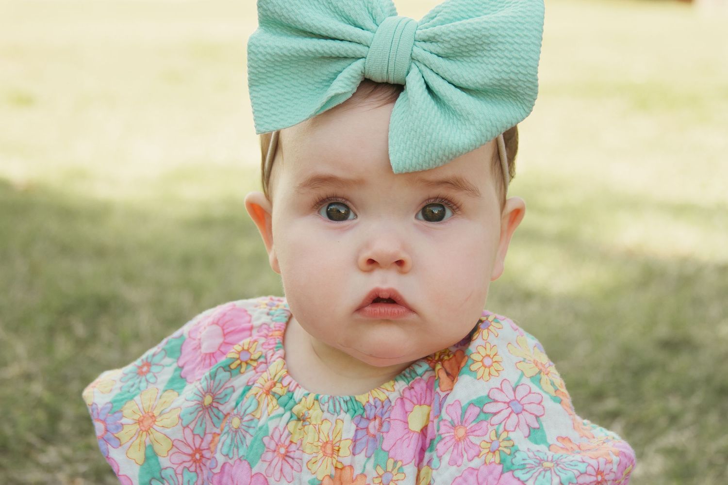 Baby sitting in grass during a spring milestone session in Blytheville Arkansas