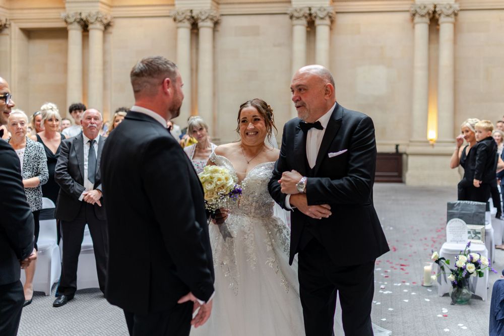 Father walks bride down the aisle at elegant outdoor wedding ceremony, groom awaiting at altar.