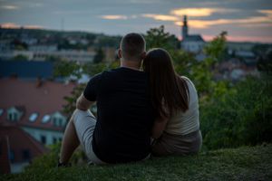 Páros fotózás naplementében, városi panorámával a háttérben.