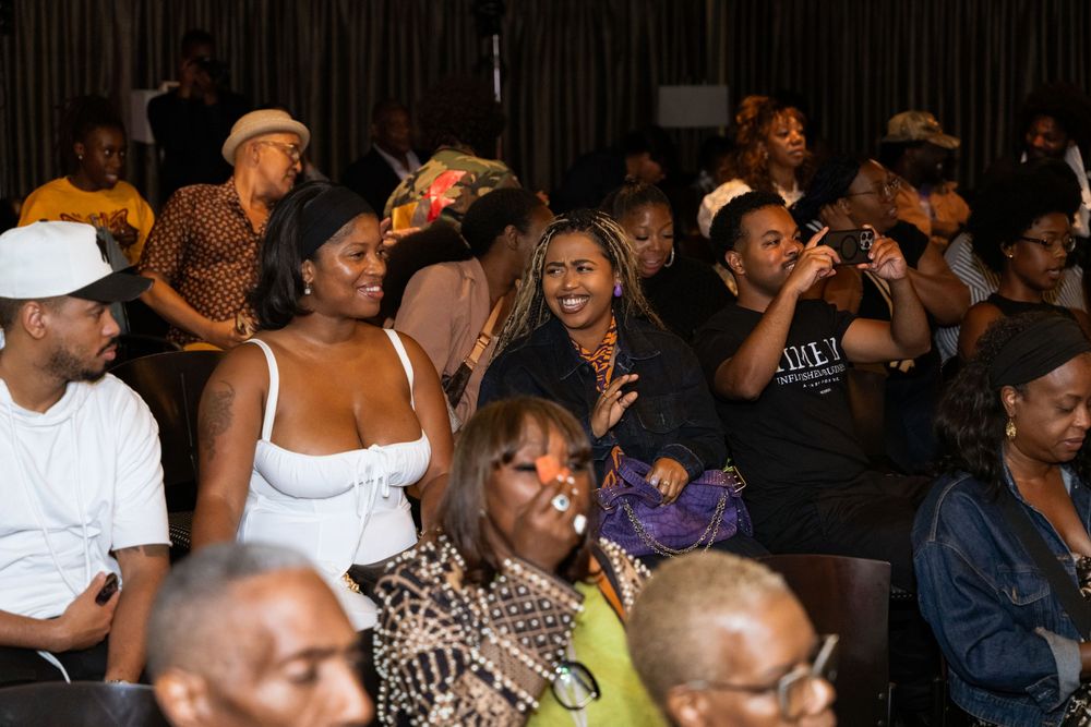 Diverse audience enjoying a lively indoor event, with smiling attendees seated in rows at a community gathering.