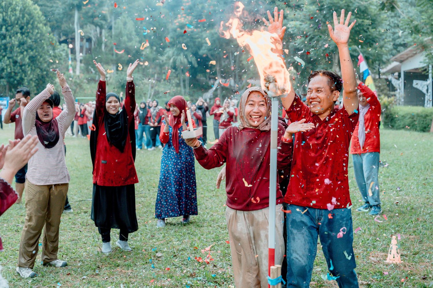 Group of people in red outfits celebrating outdoors with sparklers and confetti on a green lawn.