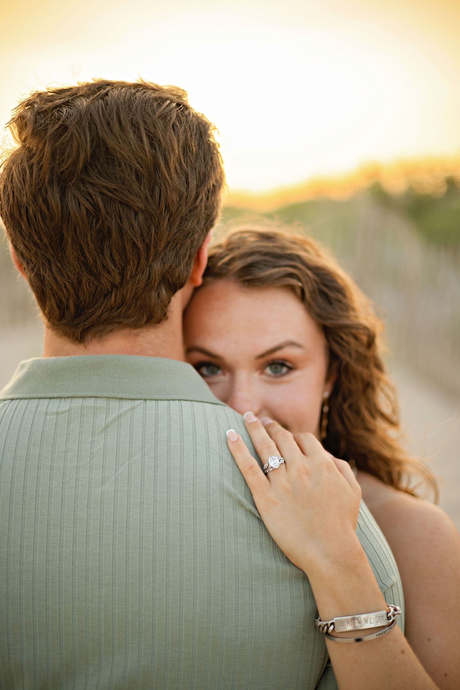 A romantic proposal scene set between rows of grapevines in a scenic vineyard with white flowers and a blanket.