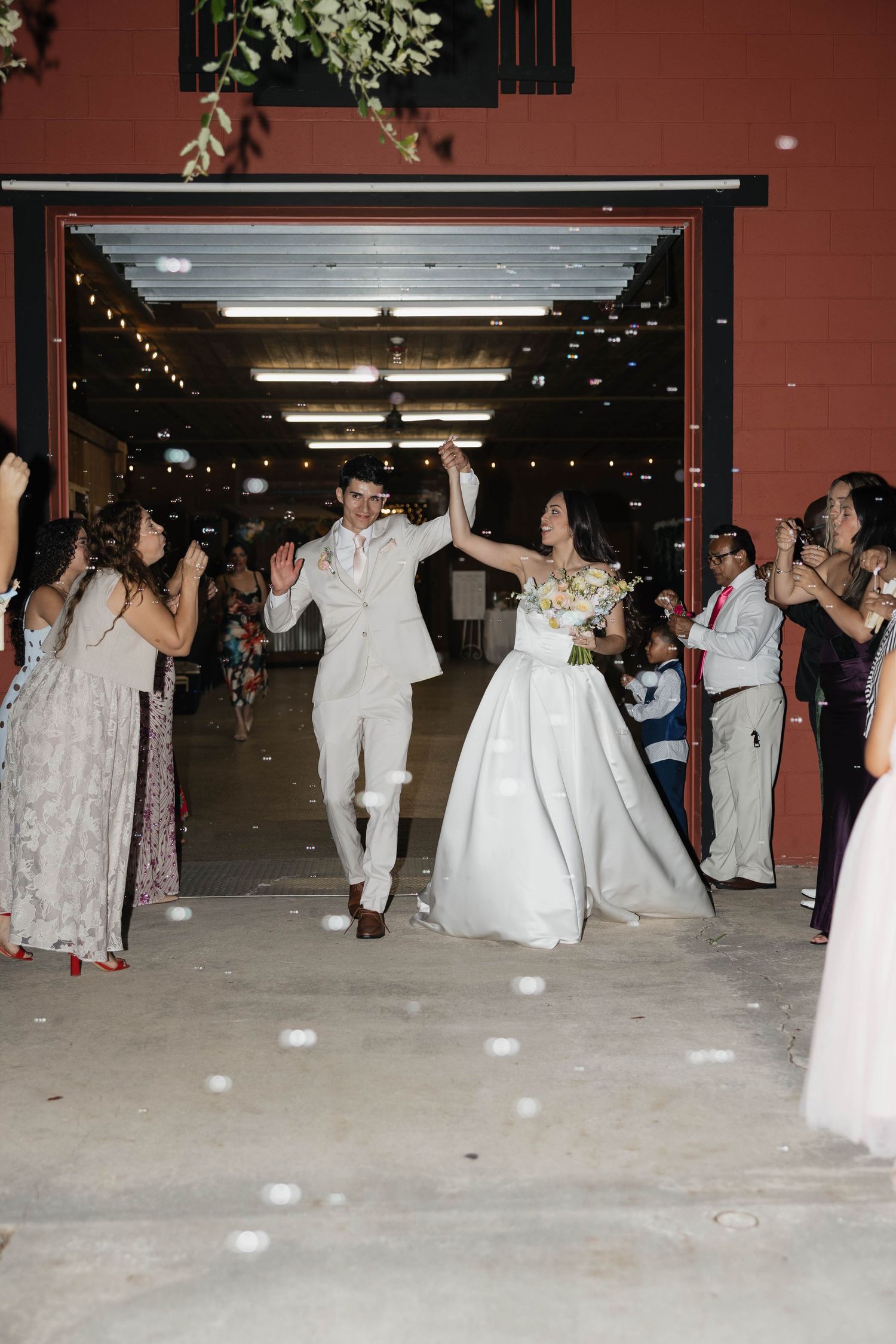 Bride and groom joyfully exit wedding venue as guests celebrate with confetti.