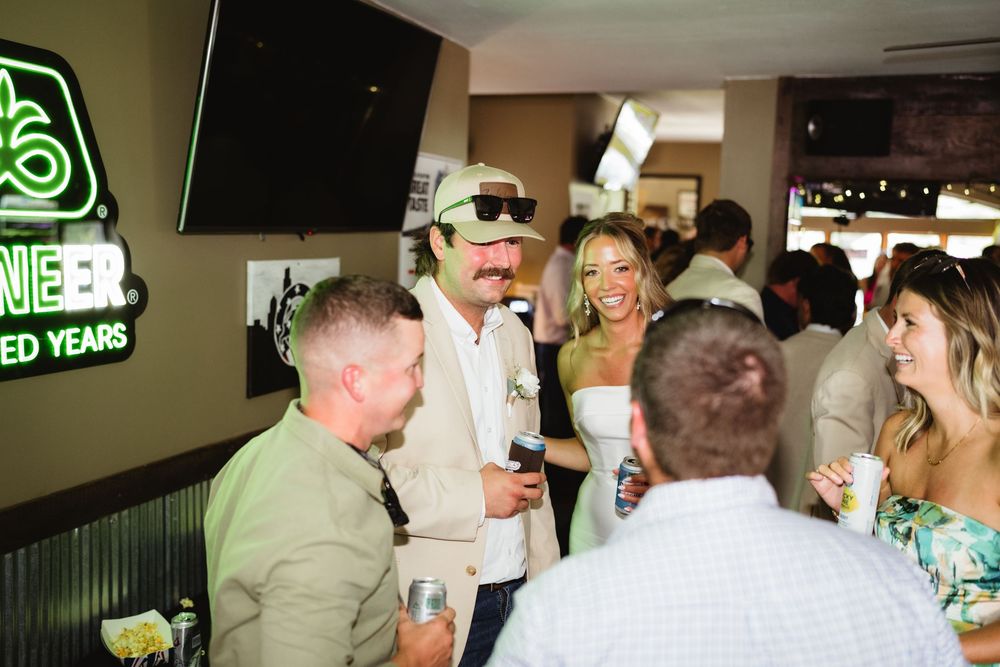 Group of stylish adults socializing at a lively bar event, with neon signs and festive atmosphere.