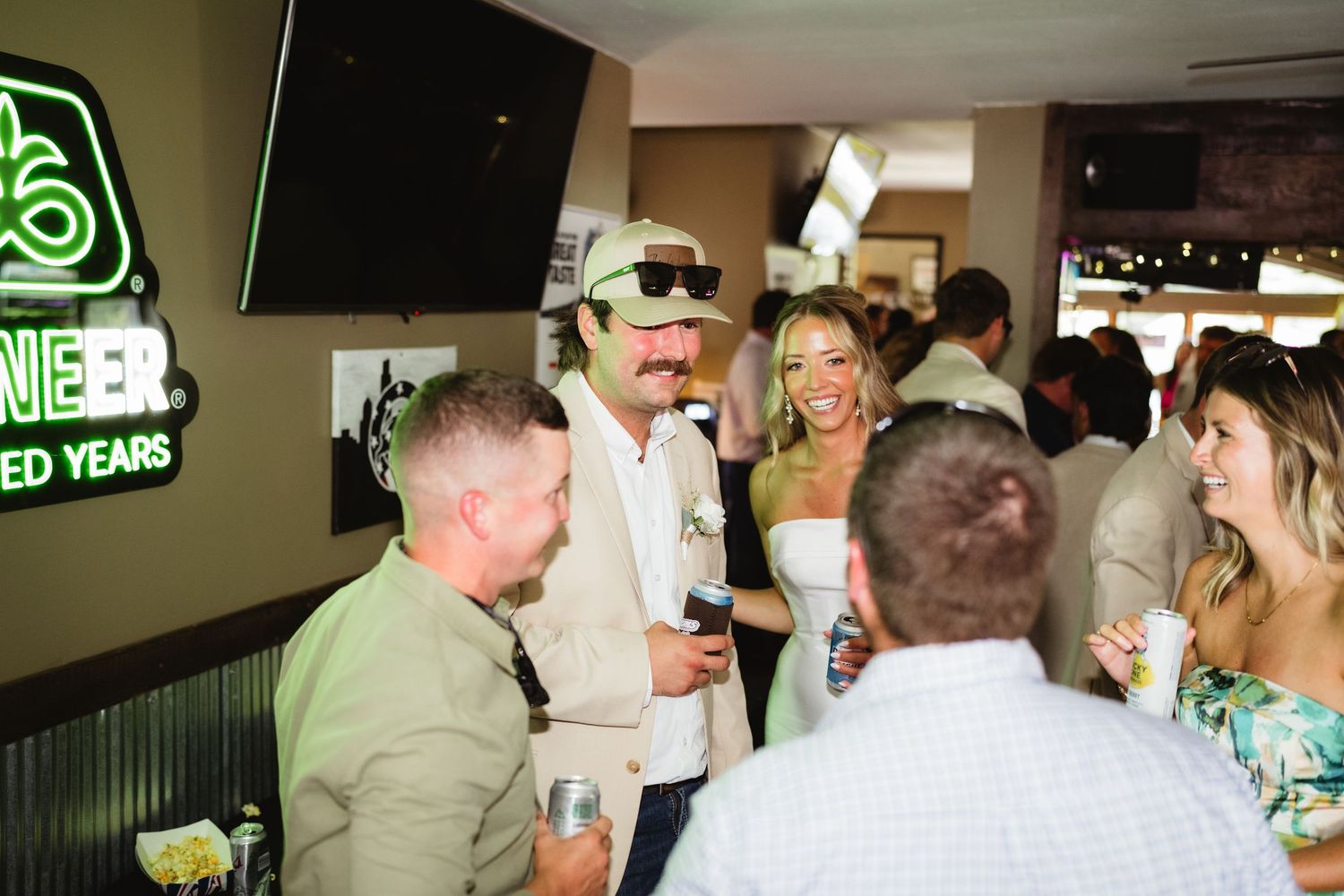 Group of stylish adults socializing at a lively bar event, with neon signs and festive atmosphere.