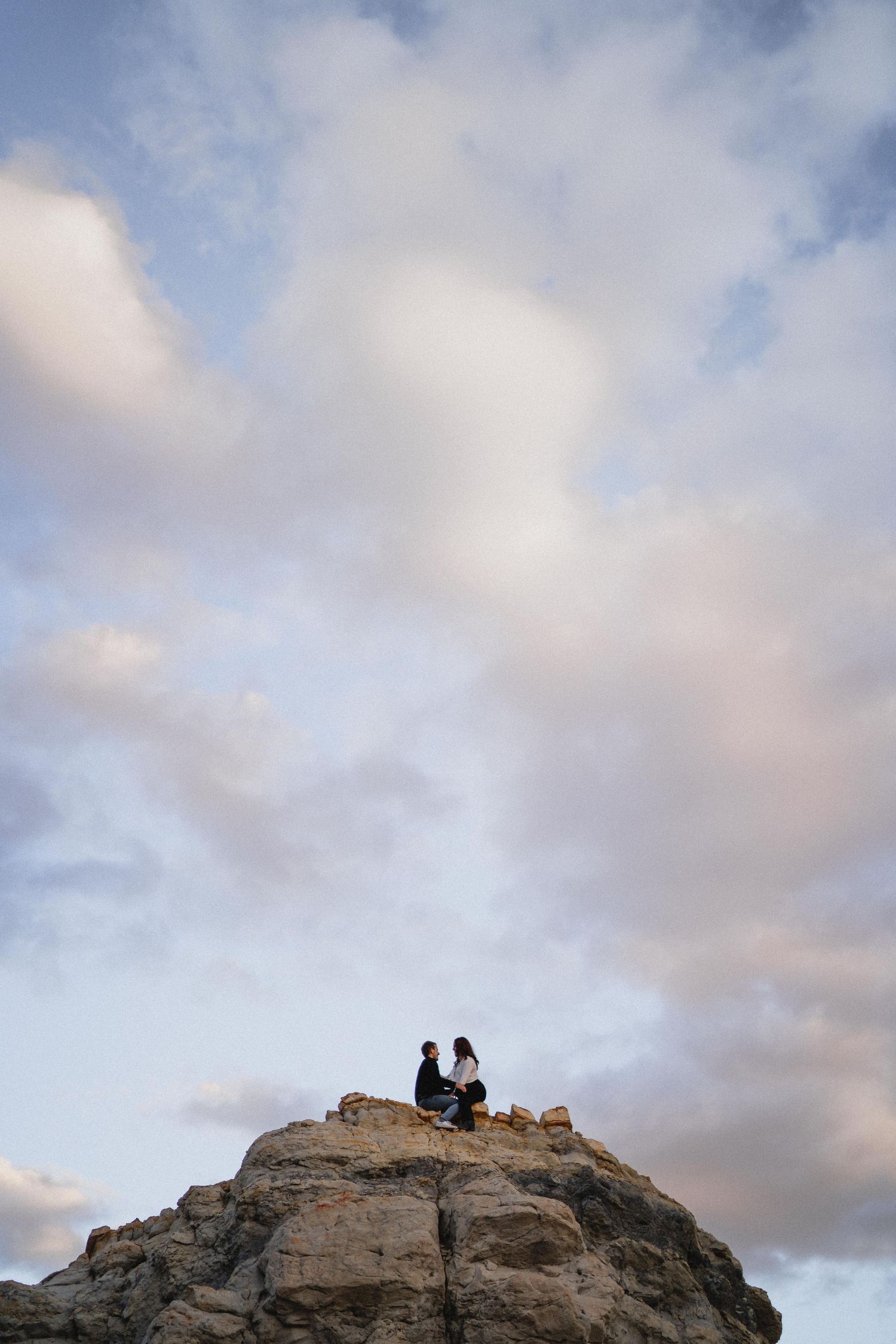 Couple dancing in a wildflower meadow surrounded by tall pine trees at golden sunset.