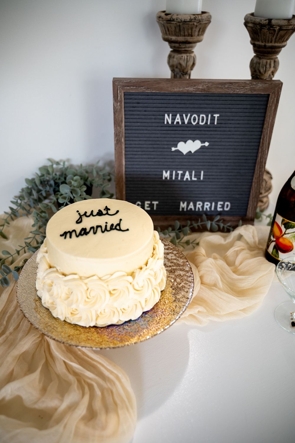 Two-tier white wedding cake reading just married beside a letterboard announcing Navodit and Mitali Get Married.