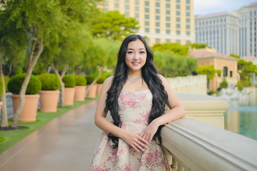 Young woman in floral dress posing outdoors near Bellagio fountains in Las Vegas on a sunny day.
