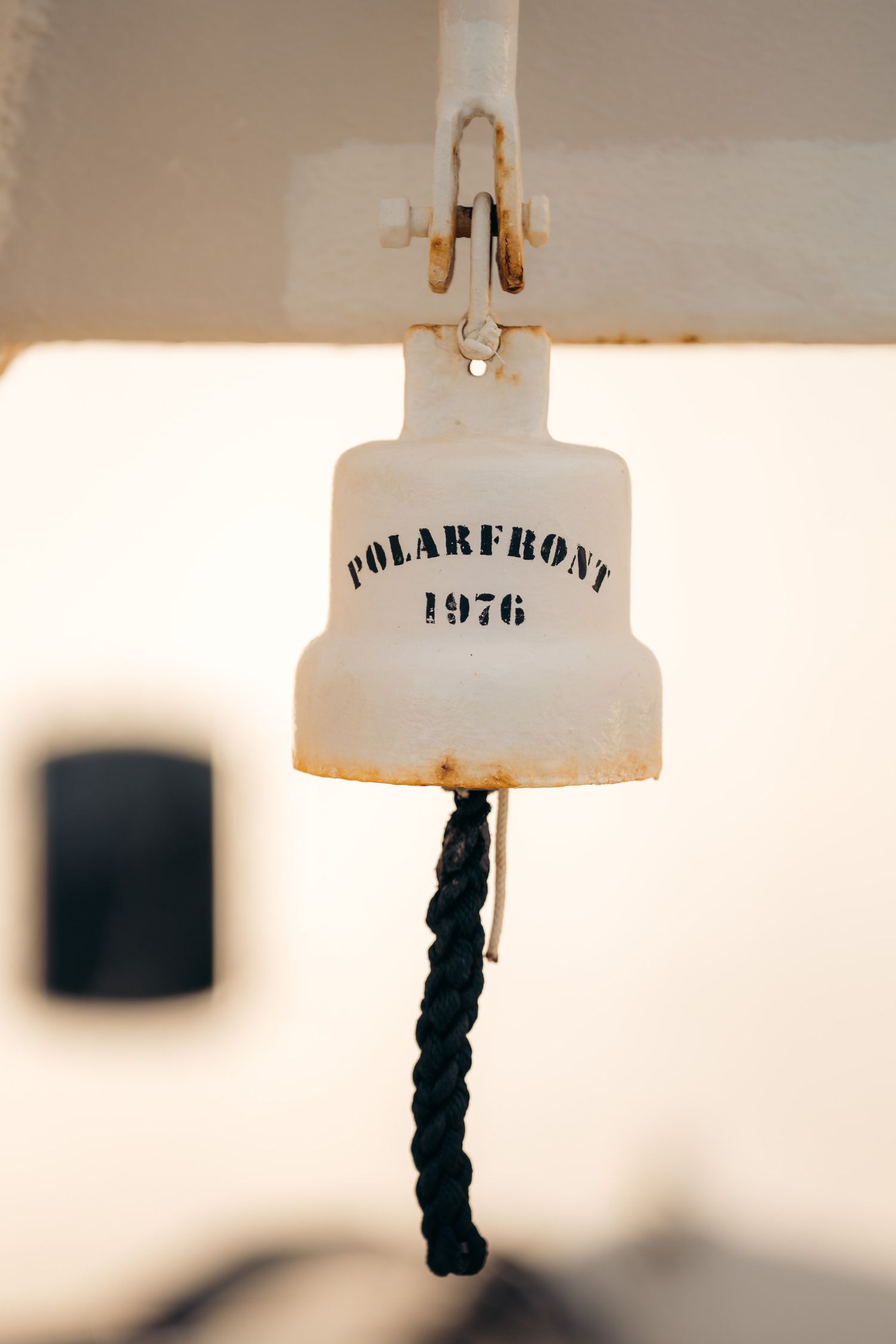 Cloche gravée du Polarfront et son cordage tressé, en gros plan sur le pont