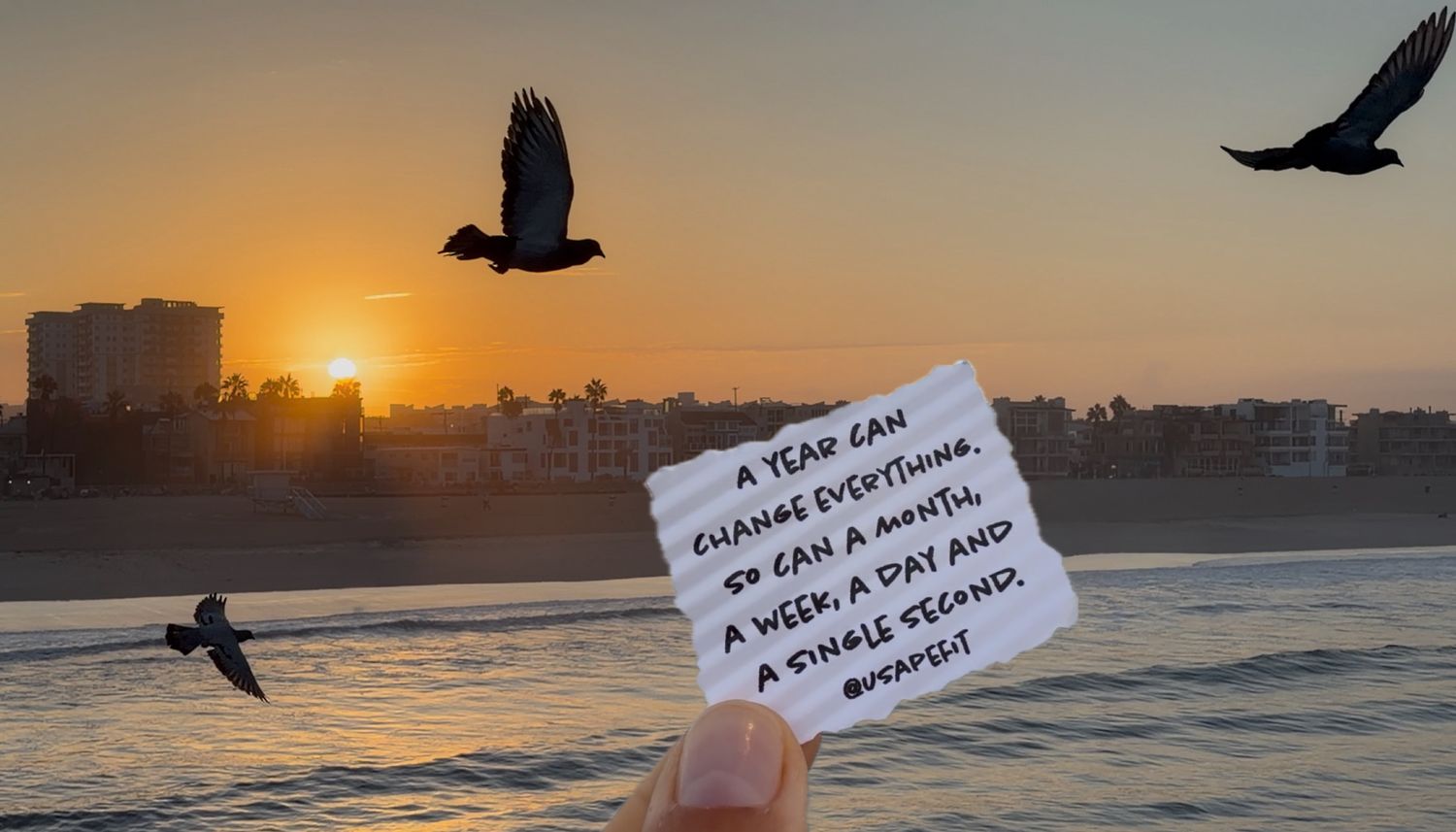 Hand holding a note about change at sunset beach with birds flying over ocean waves in golden hour light.