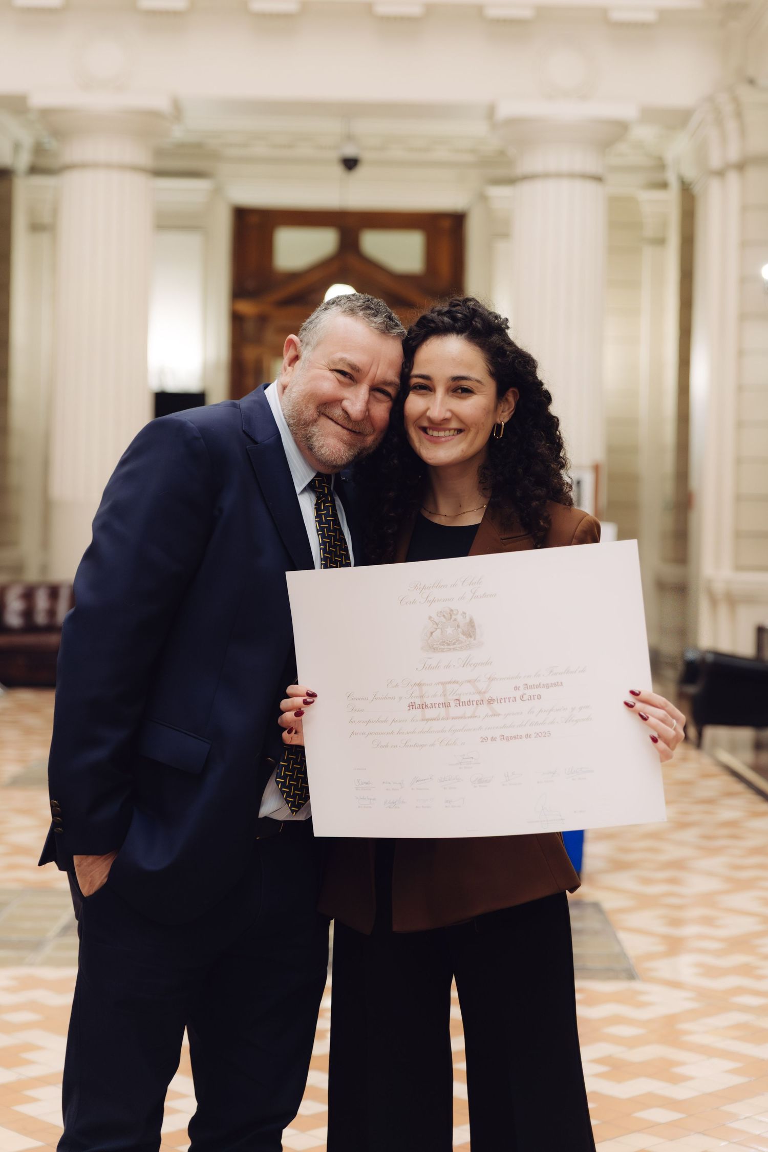 Smiling man and woman display an official certificate indoors.