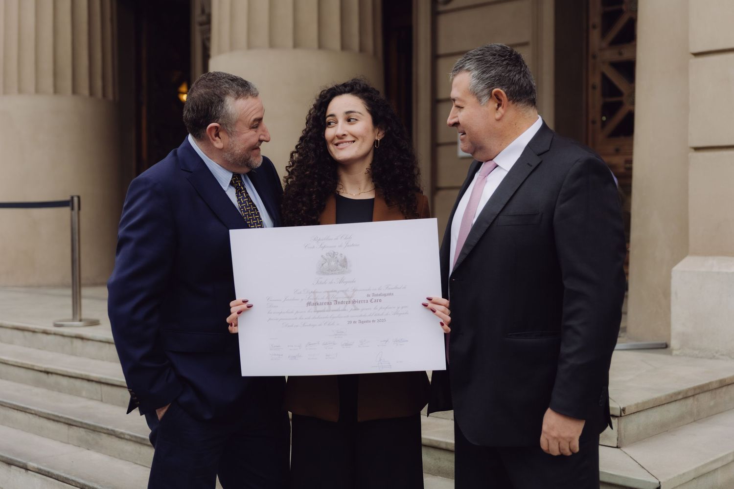 Three professionals examining official diploma certificate outside classical government building.