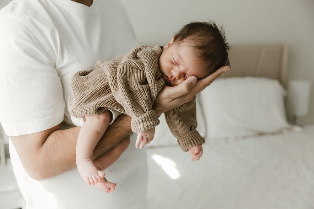 Dad poses with newborn during in-home newborn portrait session in East Tx with Tyler Tx Newborn photographer