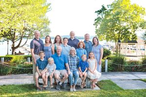 Large extended family group portrait outdoors near a waterfront, smiling together on a sunny day. Cate Park Wolfeboro NH
