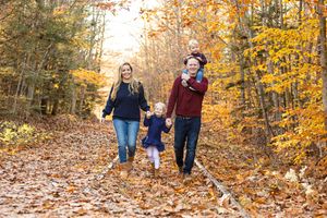 Family of four enjoying an autumn walk through colorful fall foliage in a scenic forest path. Cotton Valley Rail Trail Wolfeboro NH
