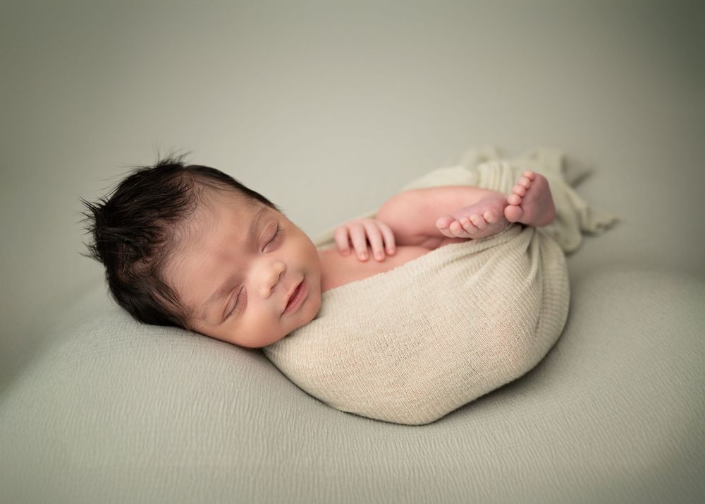 Sleeping newborn baby wrapped in a neutral pose during a studio newborn session
