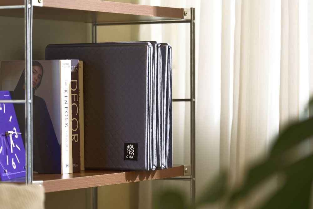 Dark fabric binder and decor book displayed on modern metal shelving unit near a window with soft natural light.