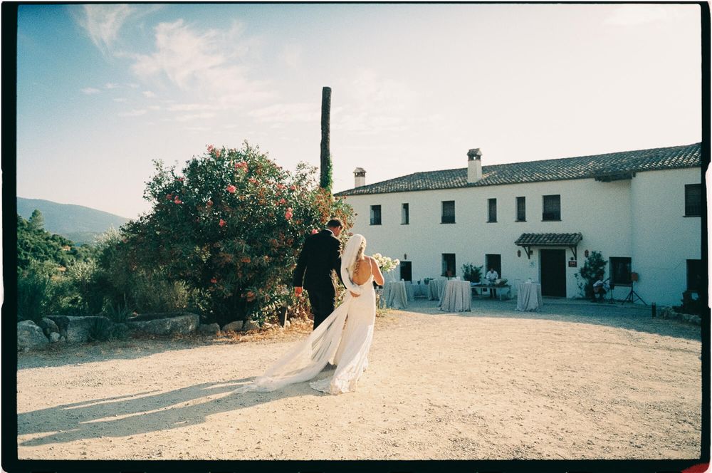 Bride and groom share a romantic moment outside a rustic white Spanish villa with mountain views on their wedding day.