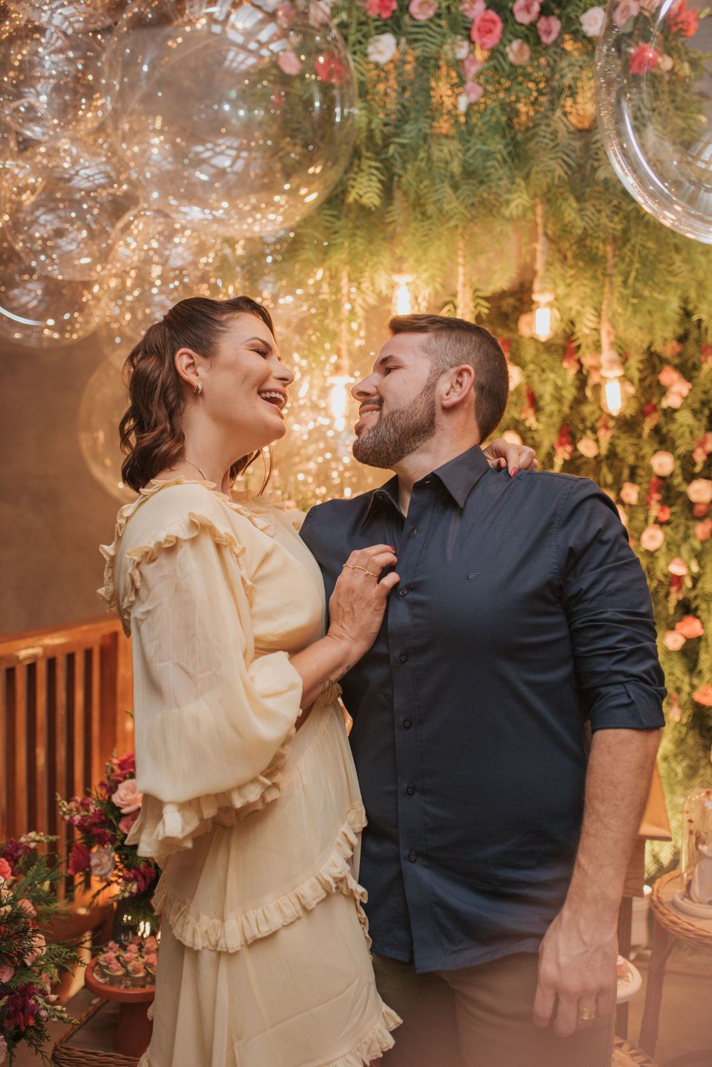 A couple shares a joyful moment under a romantic floral ceiling installation.
