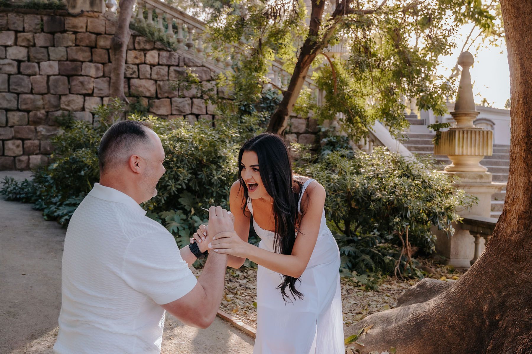 Bubbly couple laughing and kissing behind the lower waterfall stairs during a private proposal session