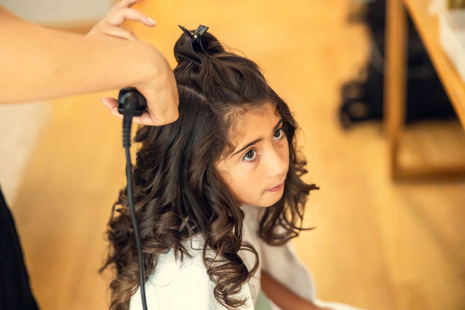Young girl getting curly hair styled with curling iron at a hair salon.