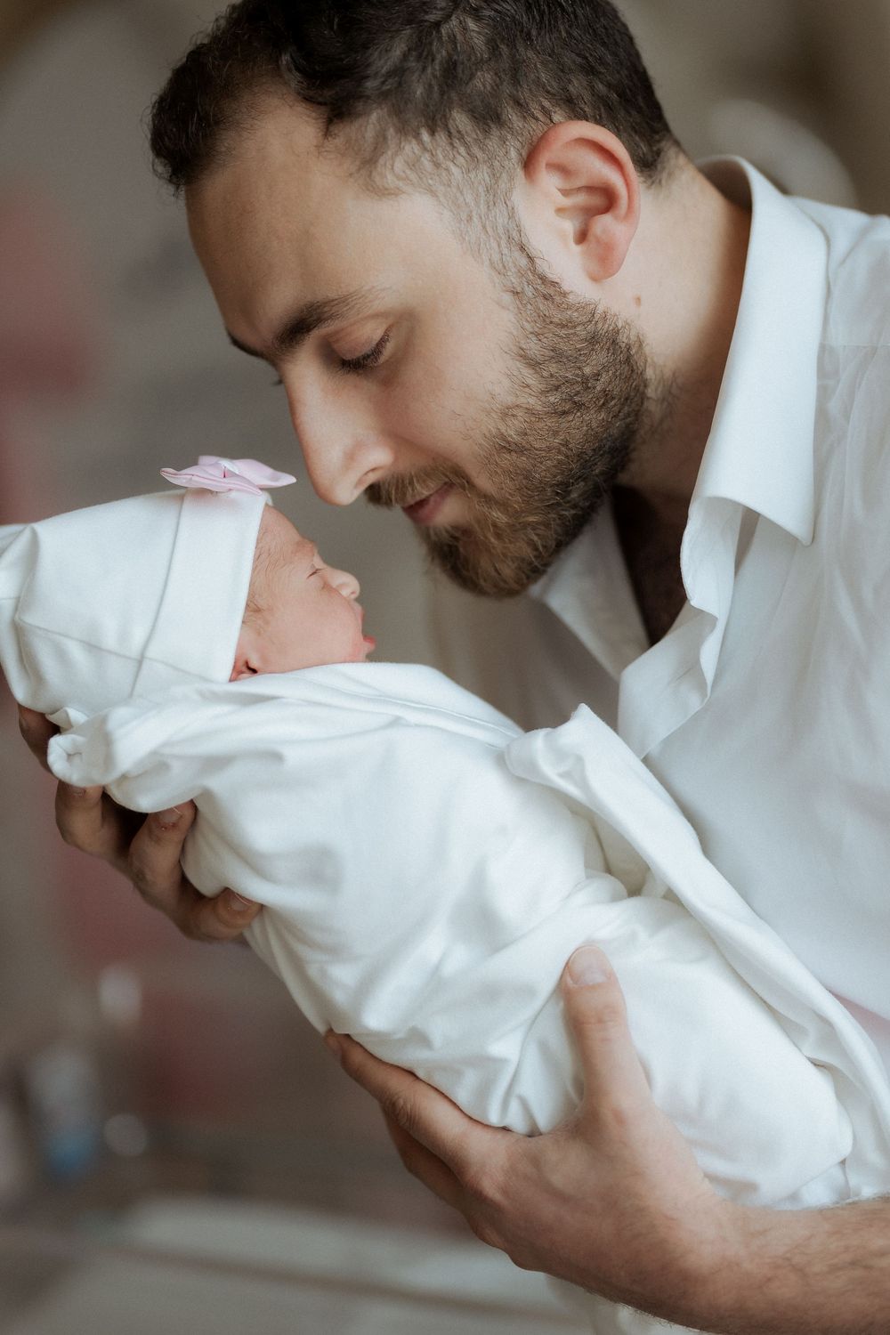 Father tenderly cradling and kissing his swaddled newborn baby