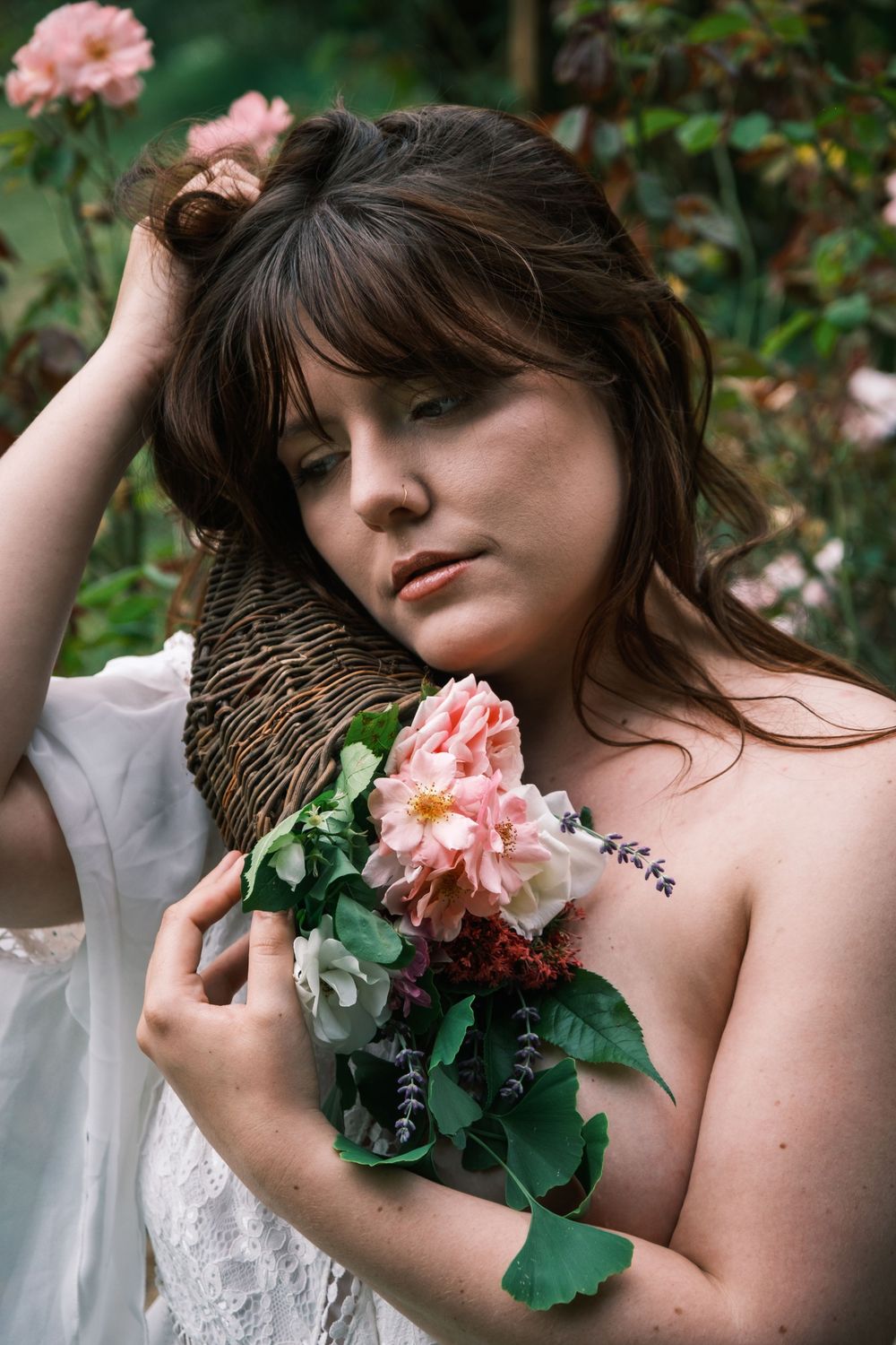 Portrait féminin en extérieur tenant un bouquet de fleurs dans un jardin fleuri.