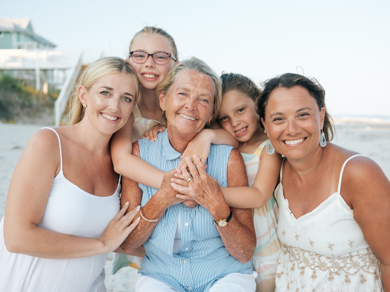 Happy multigenerational family of five embracing together on a sunny beach.