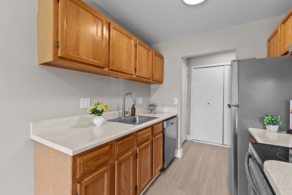 Bright kitchen featuring oak cabinetry, stainless steel appliances, and light countertops with garden view.