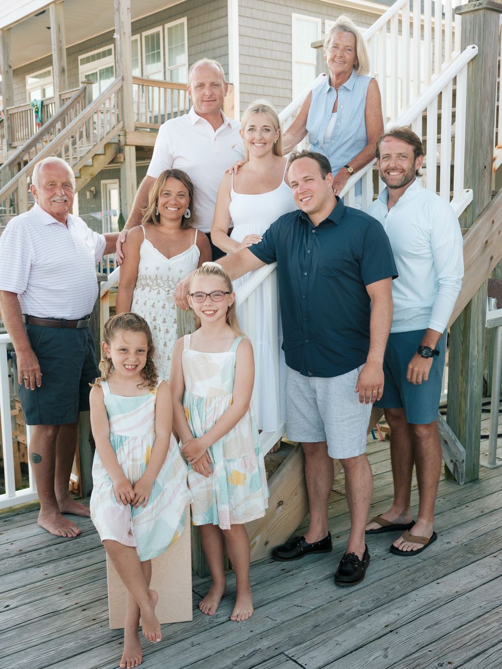 Multi-generational family poses together on beach house deck during summer vacation.