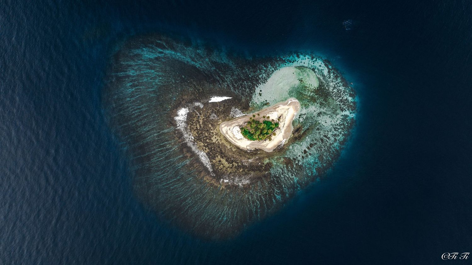 Aerial view of circular islands or atolls in deep blue ocean with turquoise reefs.