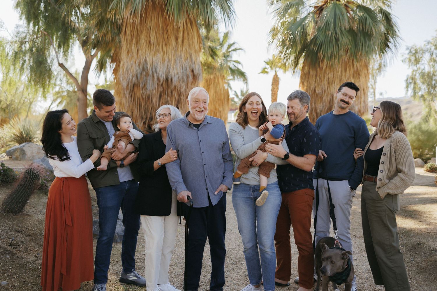Family of four posing outdoors in desert landscape, parents and two children smiling in casual attire.