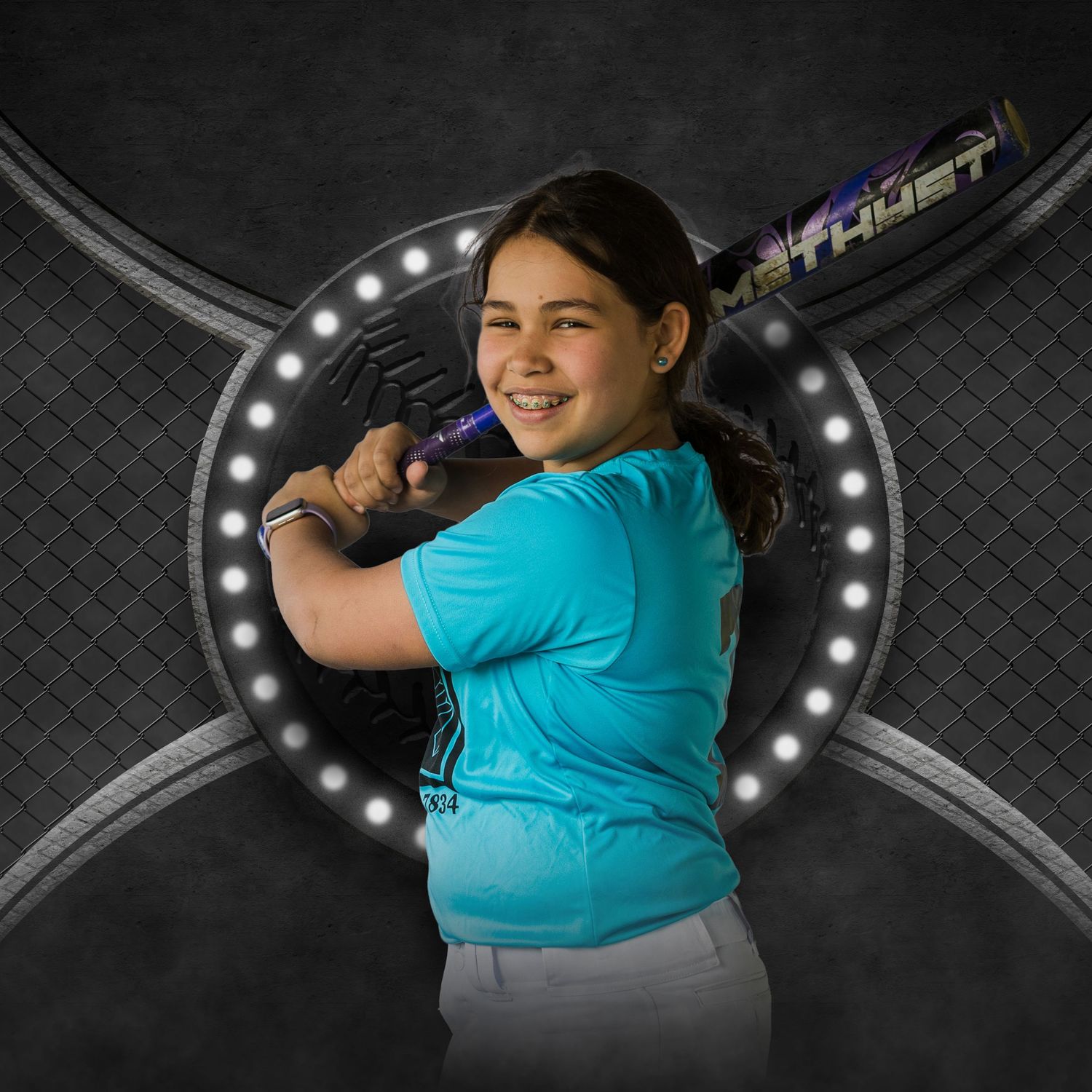 Young girl in teal shirt poses with baseball bat in sports portrait with dramatic studio lighting.