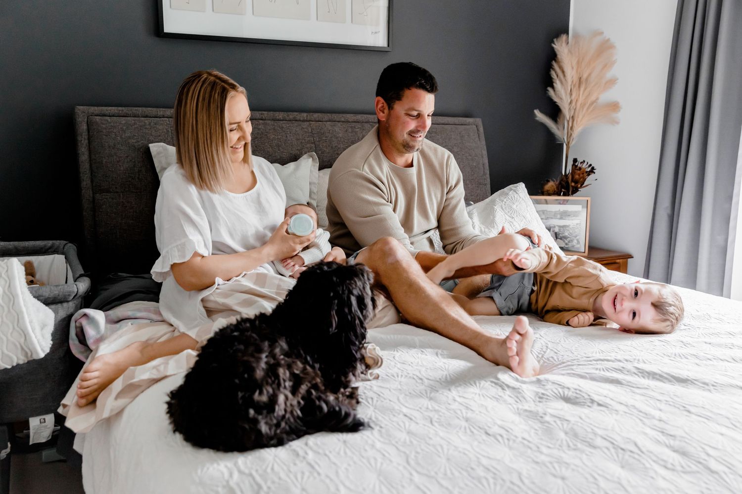 Lifestyle newborn session Adelaide — parents and siblings together on the bed with their newborn at home, photographed by Photo by Nancy