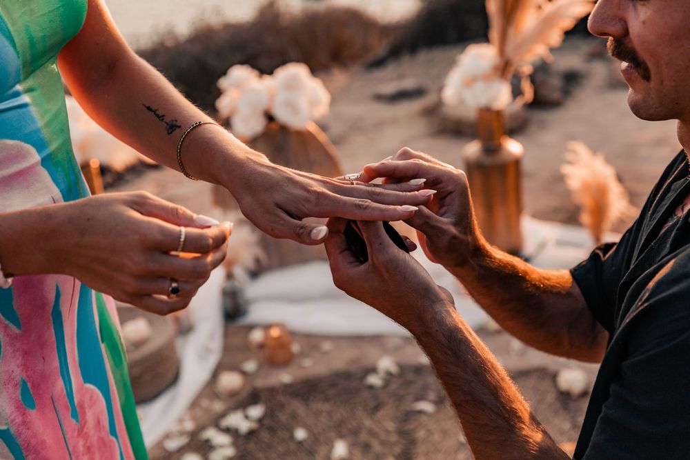 Close-up of a man sliding an engagement ring onto a woman's finger during a boho-style surprise proposal in Mallorca.