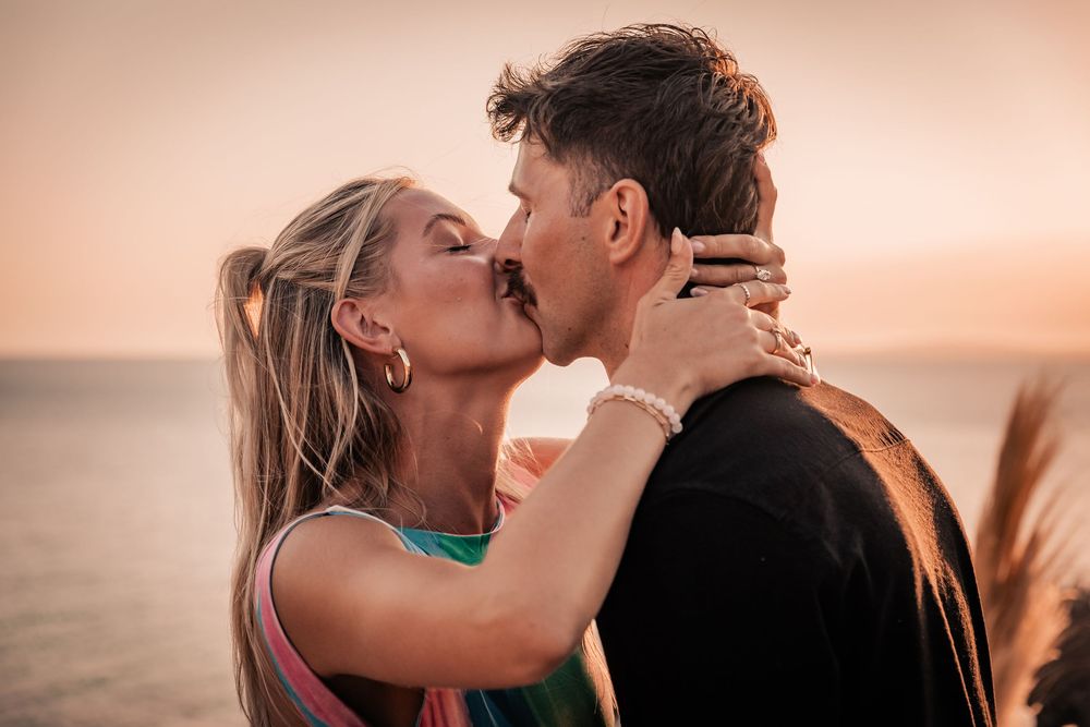An intimate portrait of a couple embracing and kissing at golden hour after a successful surprise marriage proposal in Mallorca.